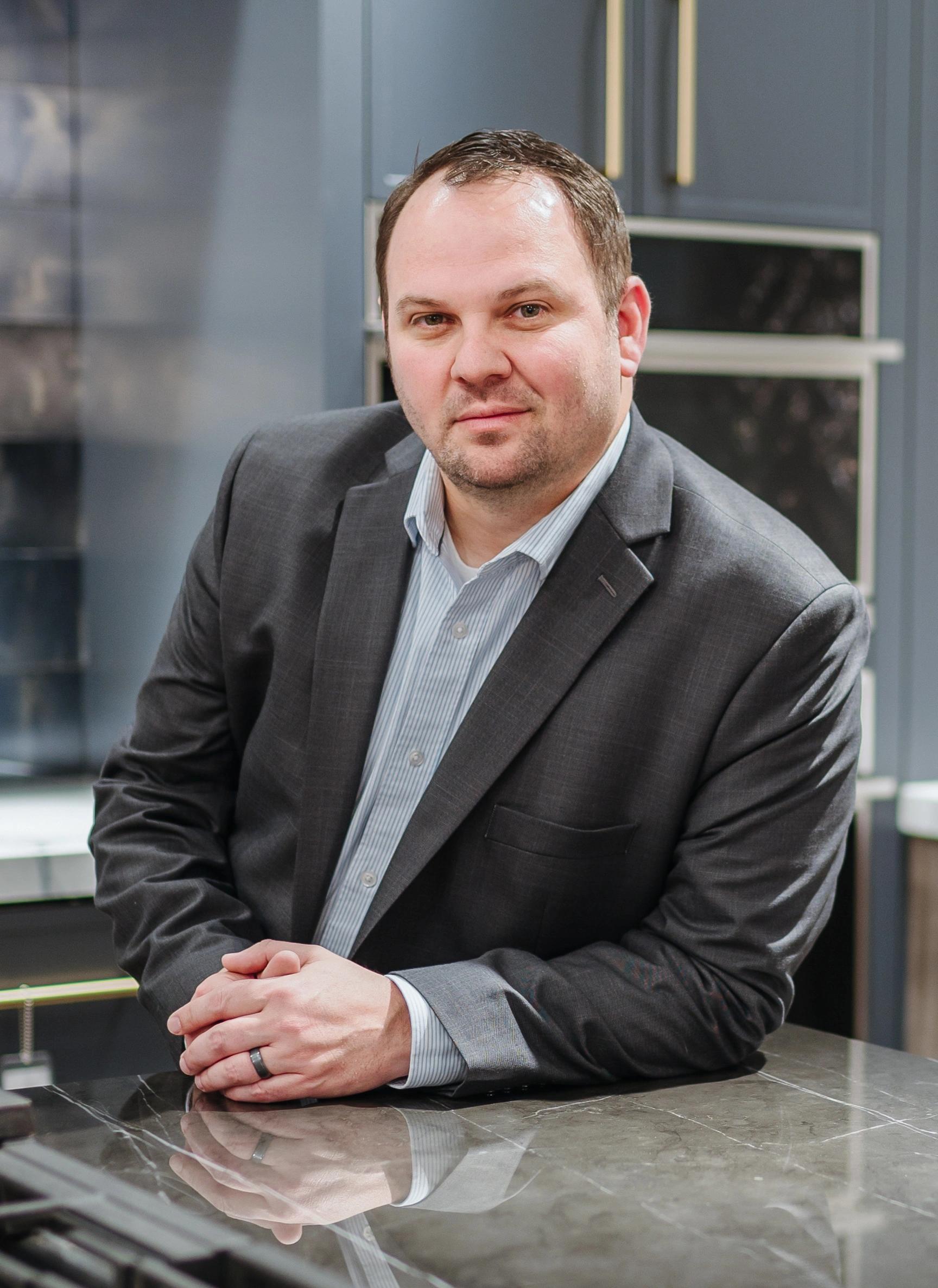 Jason Miller leaning on a dark stone counter for a portrait photo